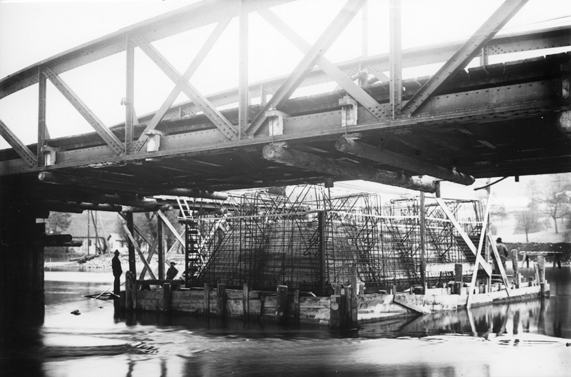 Während bei der neuen Brücke der Caisson aus Eisenbeton direkt vor Ort gegossen wurde, waren für die alte Brücke noch an Land vorbereitete Eisen-Caissons mit Mantelblechen verwendet worden.