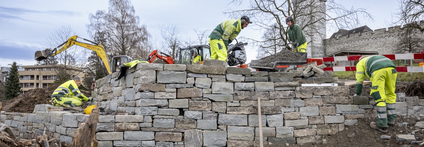 Mitarbeitende von Stadtgrün bauen eine Trockensteinmauer