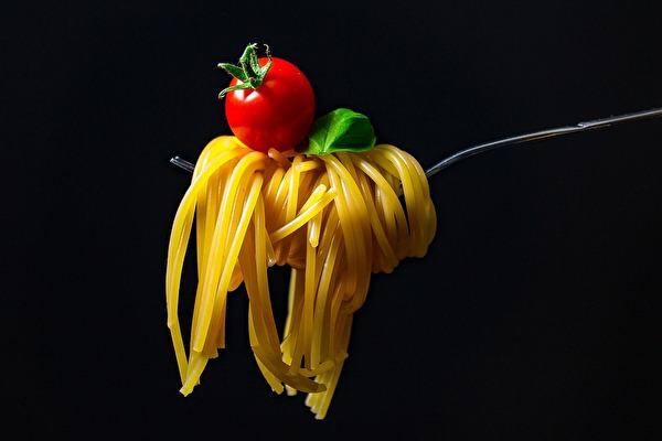 Auf dem Bild ist eine Gabel mit leckerer Pasta und einer Tomate obendrauf zu sehen!
