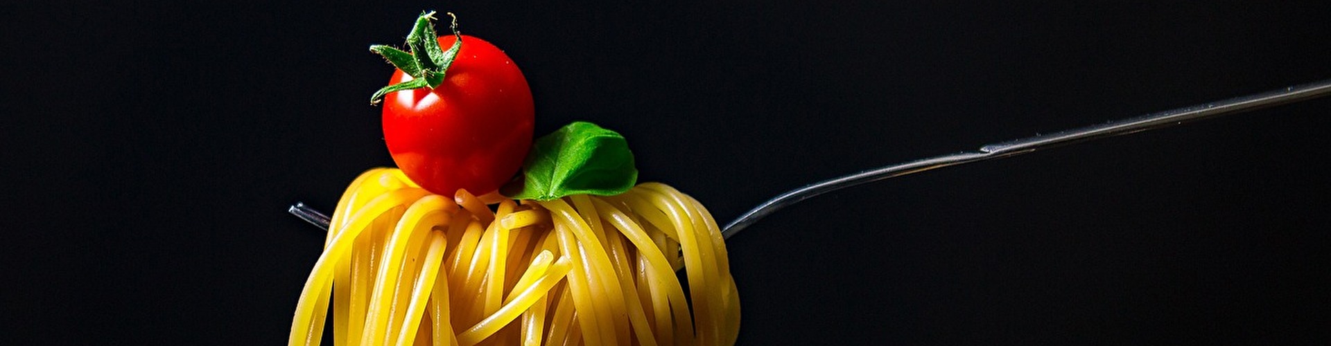 Auf dem Bild ist eine Gabel mit leckerer Pasta und einer Tomate obendrauf zu sehen!
