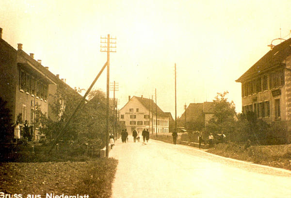 Vater Schiess sen., Schiess Fritz, Schiess Marie am Strassenrand. Der "Latschari-Platz" war Treffpunkt der Dorfkinder beim Milchholen vor der Molkerei. Rechts Handlung Kunz.