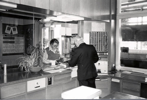 Sept. 1977
Bahnhofvorstand Fritz Künzler händigt Frau Eichenberger ein Billett aus.
In der Mitte rechts sind die Druckplatten für die verschiedenen Billette sichtbar. Damit wird im Billettdrucker "Pautze" der entsprechende Fahrauweis direkt gedruckt. Es sind somit keine Billettvorräte mehr vorhanden.