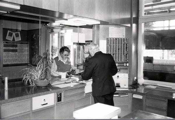Sept. 1977
Bahnhofvorstand Fritz Künzler händigt Frau Eichenberger ein Billett aus.
In der Mitte rechts sind die Druckplatten für die verschiedenen Billette sichtbar. Damit wird im Billettdrucker "Pautze" der entsprechende Fahrauweis direkt gedruckt. Es sind somit keine Billettvorräte mehr vorhanden.