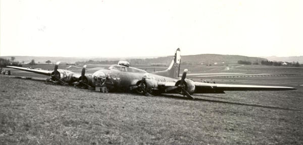 <b>Ein Bomber landet!</b>
Text-Quelle: Pdf-Dokument 0123_0135Bomber.pdf im Fotoarchiv der Gemeinde Niederglatt
Foto: vom Zeitzeugen Josef Bertschi, Jg. 1920, Landwirt v. Höri

<i>«Am Donnerstag, 13. April 1944, 14.30 Uhr ging im Gemeindebann Niederglatt im "langen Zinggen" kurz vor dem Wald ein amerikanischer Bomber, eine sogenannte "Fliegende Festung" nieder. Die Mannschaft 11 Mann, blieb unverletzt.»

Die Maschine soll nach B.R. in Dübendorf beschossen worden sein. Sie flog niedrig über das Bahnhofsgelände von Oberglatt und drehte über dem Bahnhof von Niederglatt nach Nordosten ab. Augenzeugen befürchteten, dass die Maschine kaum mehr die Strecke bis über die Glatt schaffe. B.R. fuhr mit dem Auto zusammen mit J.Sch. sofort zur Notlandestelle und fotografierte.

Die Maschine war mit eingezogenem Fahrwerk gelandet. Nach etwa 200 m war sie, mit abgebogenen Propellern, auf ansteigendem Terrain stehen geblieben. 3 Mann flüchteten sofort in den Wald, denn damals war bekannt, dass die Deutschen die Besatzungen erschossen. Sie wurden von Holzhauern in Kenntnis gesetzt, dass sie sich in der Schweiz befänden. Auch die im Flugzeug verbliebenen Amerikaner freuten sich natürlich über diese Tatsache.

Die Bombenschächte des Flugzeugs waren leer, die Bord-Maschinengewehre geladen, aber es war nur noch wenig Munition vorhanden. Wahrscheinlich war die Besatzung in Kämpfe verwickelt gewesen.

Die Kunde von der Notlandung verbreitete sich in Windeseile und aus allen umliegenden Dörfern strömten Schaulustige herbei. Bald aber erschien Militär auf dem Platz und schaffte Ordnung. Das Flugbenzin wurde herausgepumpt. Allzu Neugierige wurden mit Fr. 10.- gebüsst. Die Maschine wurde an Ort und Stelle demontiert und abtransportiert.

In unvergesslicher Erinnerung ist bei verschiedenen Niederglattern die Kaugummi-Geschichte. Damals waren sie als Knaben mit den Velos zum Bomber gerast. Die erleichterten Amerikaner verteilten den Kindern Kaugummi. Diese sollen Aufputschmittel enthalten haben (für übermüdete Soldaten). Die Kinder schlossen in der darauffolgenden Nacht kein Auge!</i>

Auch hier gibt es noch eine Geschichte des Niederglattner Augenzeugen Hans Bergmann:
http://www.zuonline.ch/blickpunkt/pdf/130404.pdf
