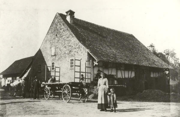 Aufnahme 1892
Dieses Foto zeigt das Haus der Familie Mahler bei der unteren Glattbrücke. Die Frau in der Bildmitte ist die zweite Ehefrau des Schuhmacher Gottlieb Schmid, der 1885 nach Niederglatt kam. Diese Frau starb am 1. Juni 1893 am Kindbett, nachdem sie am 6. Mai 1893 einem Knaben das Leben geschenkt hatte.