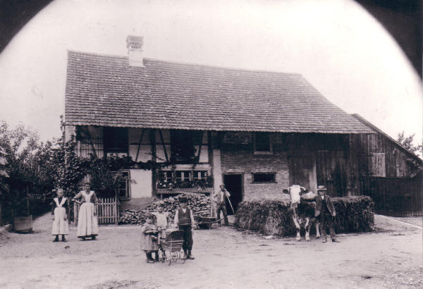 Foto um 1900 herum: An der Stelle wo die heutige Post steht, stand einmal das Bauernhaus der Familie J. Schmid.
Damals gab es viele solche typischen "Dreisässenhäuser". Unter einem Dach befindet sich quer, der Wohnteil, der Stall und das anschliessende Tenn. Die Tiere wurden vom Tenn her gefüttert.