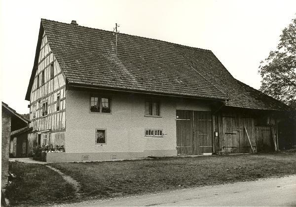 <i>Baujahr 1664, Foto 1965</i>
In den 1960.er Jahren lebte Jean Volkart, bekannt als Chuefer Schang, in diesem Haus. Im Haus befand sich einst die Zehntenscheune der ehemals selbständigen Gemeinde Nöschikon. Erst 1699 erfolgte der Zusammenschluss zur politischen Gemeinde Niederglatt. Das Haus war ein Riegelfachwerkbau mit zum Teil geschweiften Balken.
In diesem Haus lebte von 1829-1908 Salome Volkart. Sie war sehr gläubig und konnte durch Handauflegen Krankheiten und Wunden heilen.