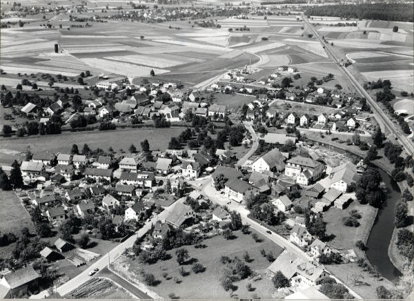 Foto ca. 1962
Die Aufnahme zeigt wie die Sonnenbergstrasse noch direkt in den Löwenplatz einmündete. Am Rande der Grafschaft, an der Bachenbülacherstrasse, werden vier neue Häuser gebaut. Der alleinstehende Silo, oben links, wurde 1962 erstellt, bevor die Siedlung Ernst Müller, im Saali 1963/64 fertig gebaut wurde.
