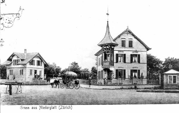 <b>Ein Stück Dorfgeschichte</b> (Foto zwischen 1903 und 1909)

Vor dem fünften Postgebäude steht die 4-5plätzige Postkutsche (<i>Berline</i>), die von 1902-1909 benützt wurde.
Das kleine Haus links ist das Geburtshaus des "Schützenhaus Berti". Allerdings steht das Schützenhaus, das ihm den Beinamen gab, nicht mehr. Es hatte eine äussere, hölzerne Treppe und ist auf dem Zehntenplan von 1765 tatsächlich mit "Schützen Haus" angeschrieben. Es war Teil der "Zielstatt Niederglatt".
Und dieser "Schützenhaus Berti" hatte besondere Fähigkeiten. Er brachte es im Militär bis zum Major und wurde Schulpräsident von Niederglatt. Als 18xy gegenüber seinem Geburtshaus das grosse Bauernhaus abbrannte, liess er an dessen Stelle das Haus mit dem markanten Ecktürmchen bauen, eben die Post.
Von diesem Türmchen aus hielt Schulpräsident und Major Volkart jeweils der auf dem Löwenplatz lauschenden Bevölkerung die 1.-August-Ansprache. Eine dieser Reden wird heute noch im Gemeindearchiv aufbewahrt.
Die Untersuchung beim erwähnten Brandfall leitete der als schlau und tüchtig geltende Statthalter Ringger von Niederglatt . Er stellte Brandstiftung fest und konnte den Täter überführen.
Vor der Post rechts steht das Waaghaus mit der Brückenwaage. Ganz links im Bild sehen wir die Anbindestange für die Pferde und dahinter die Haferkrippe. Beides stand vor dem Restaurant Löwen, den Hafer führten die Fuhrleute selbst mit.
(<i>Text: nach Angaben von Hangeri (Heinrich) Volkart und Unterlagen aus dem Gemeindearchiv</i>)
