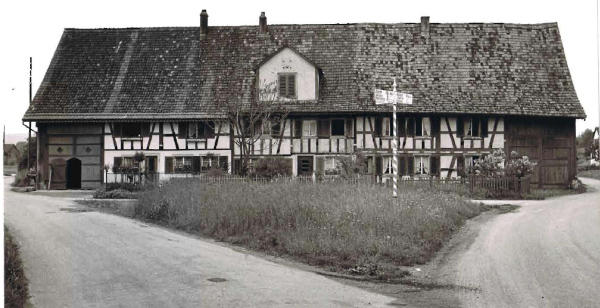 Foto Mai 1965
Das <b>Haus im Gärtli</b> steht schmuck und breit da, die Strassen führten ursprünglich nur ganz knapp an den Hausecken vorbei. Der Hausteil rechts geht auf das Jahr 1680 zurück, der links auf 1820 (laut Gebäudeversicherung).
Die Mitte wurde früher als Stall und Scheune genutzt.
Wegen des hohen Grundwasserspiegels entlang der Glatt, ist dieses Haus nicht unterkellert.
<i>(Text: Gemeinde Archiv)</i>
