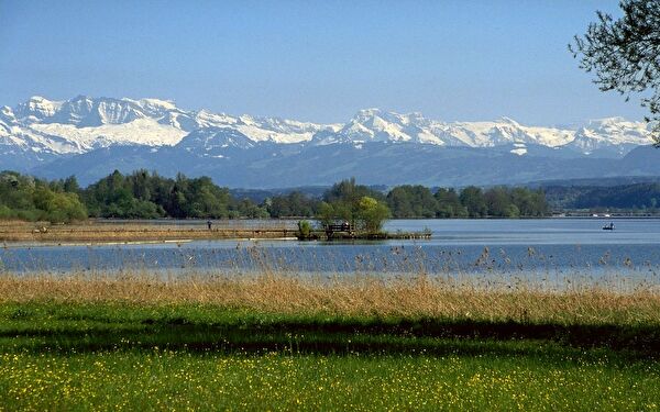 Sicht über den See im Frühling mit Inselisteg und Alpen im Hintergrund