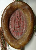 Ovales rotes Siegel in hellbrauner Siegelschale mit breitem Rand. Im Siegel eine Darstellung des Bischofs, in einem gotischen Gebäude sitzend, darunter zwei Wappen, eines mit Schlüssel, das andere mit dem Steinbock des Bistums Chur.