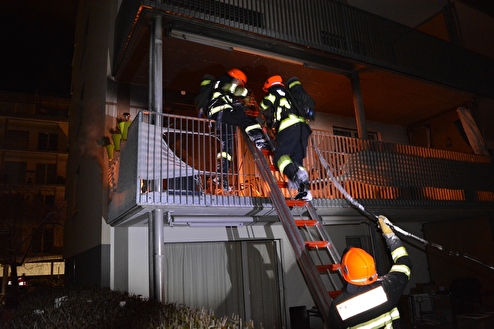 Feuerwehrleute beim Betreten des Balkons über eine Anstellleiter mit dem Schnellangriff.