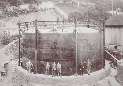 Foto des Gasometers von 1897, mehrere Männer stehen auf der gemauerten Umrandung sowie auf der Gasglocke.