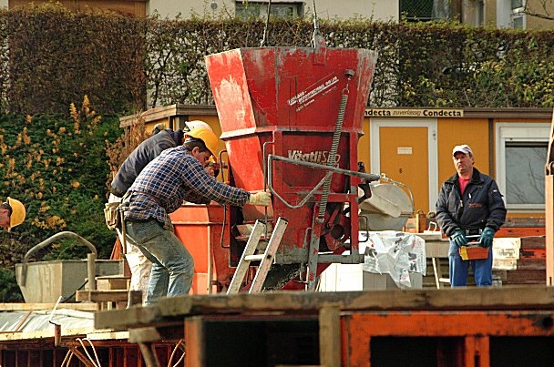 Bauarbeiter beim Betoneinfüllen in die Schalungen der Aussenwände im Untergeschoss des Erweiterungsbaus.