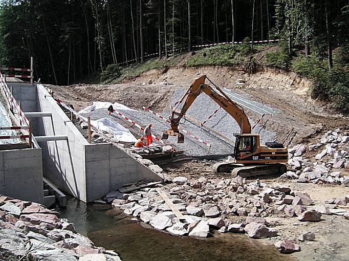 Zurzeit laufen am Dammbauwerk die Arbeiten an der Hochwasserentlastung. Die Rinne wird mit Granitblocksteinen verkleidet. Aus diesem Grunde werden jetzt während ca. zwei Wochen keine Dammschüttarbeiten erfolgen, bis die Hochwasserrinne genügend hoch erstellt ist.