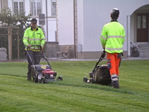 Berufslernender mit Berufsbildner beim Rasenmähen