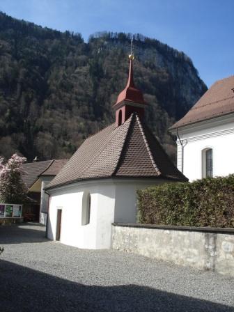 An der südlichen Peripherie des Friedhofes steht das 1693 erneuerte Beinhaus, eine niedrige Kapelle mit hohem Ziegeldach und polygonalem Chorabschluss. Es bildet mit seinen beiden seitlichen Portalen ein offenes Torhaus, als Durchgangspforte zum Friedhof und zur Kirche. Das Schiff ist mit einer Stucktonne überwölbt. Das Gesims läuft hinter der Scheidewand in den hohen, runden Chor
hinein. Die alte Bezeichnung ’Beinhaus’ wird durch die Totenschädel in den beiden Nischen an der Rückwand erklärt.