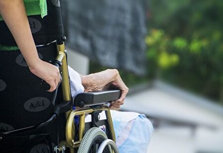 Freiwillige schiebt eine Persone im Rollstuhl