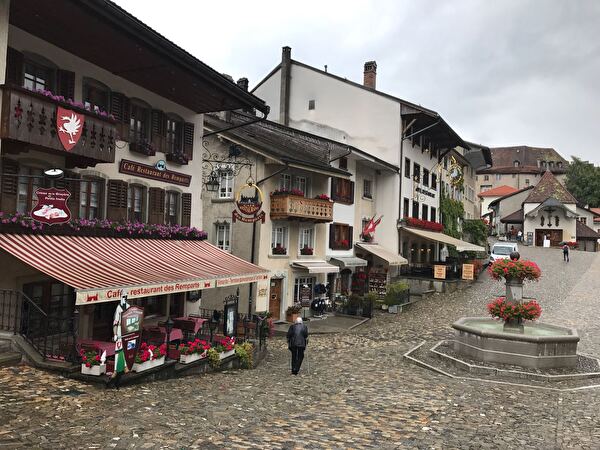 Sicht auf Dorf mit Brunnen in Gruyères bei Regen