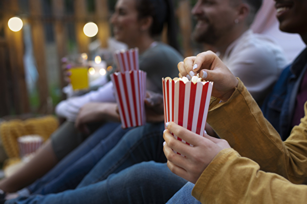 Junge Freunde im Kino beim Popcorn essen