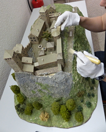 Ein Zivilschützer säubert ein Burgmodell mit Schwamm und Pinsel.