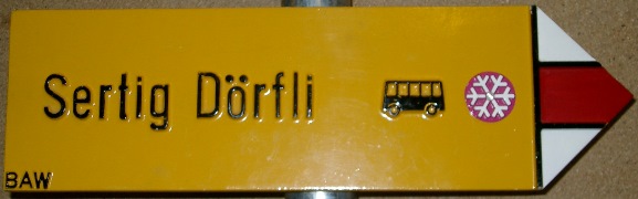 Gelbes Wanderwegschild Sertig Dörfli mit Buspictogramm und Winterwanderwegsignet