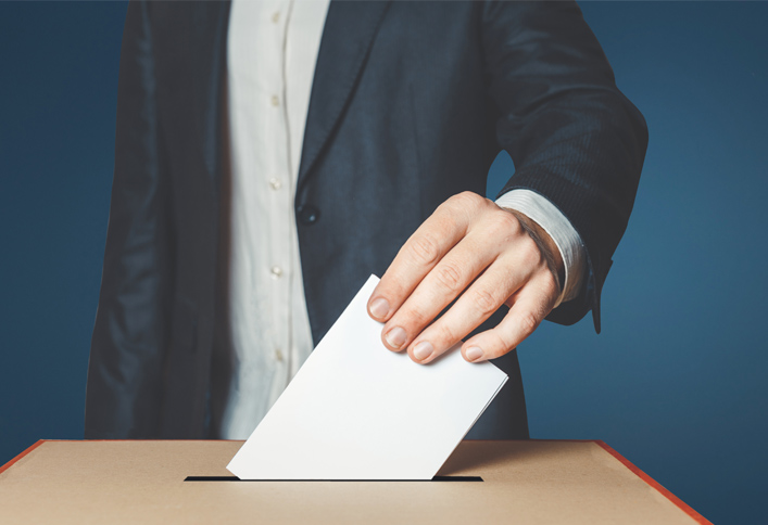 Photo d'un bulletin de vote glissé dans une urne de votation