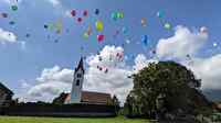 Bunte Ballone steigen vor der Kirche in den Himmel.