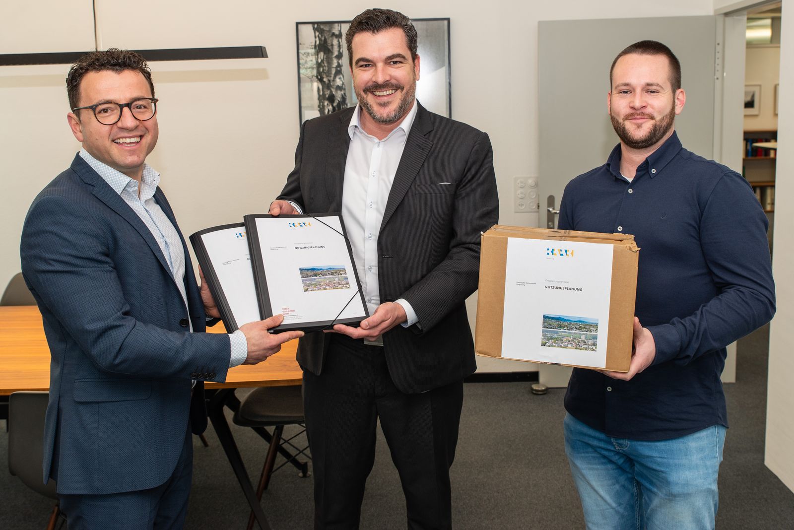 Gemeinderat Zari Dzaferi (links) und Pascal Strüby, Leiter Siedlungs- und Verkehrsplanung (rechts), durften die gemeindliche Nutzungsplanung dem Zuger Baudirektor Florian Weber persönlich überreichen.