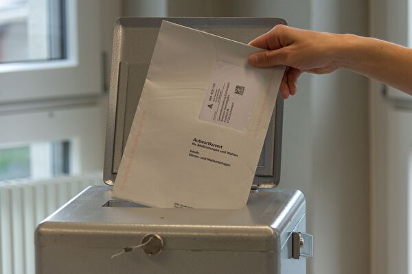 Stimmcouvert wird in die Urne eingeworfen