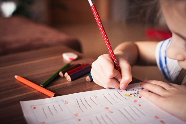 Mädchen schreibt mit einem Stift auf ein Blatt