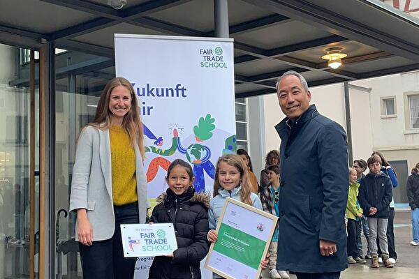 Stadtrat Jigme Shitsetsang und Catherine Wälti von Swiss Fair Trade überreichen zwei Schülerinnen die Auszeichnung von Fair Trade School