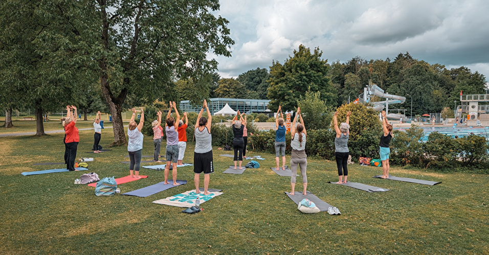 Menschen draussen beim Yoga.