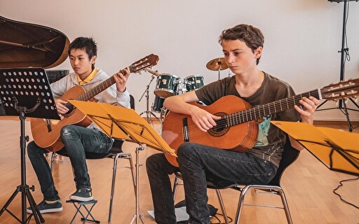 Zwei Jugendliche an der Gitarre.