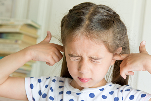 Ein Mädchen hält sich die Ohren zu.
