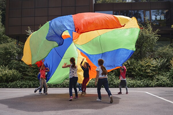 Kinder mit einem grossen, farbigen Tuch in der Luft.