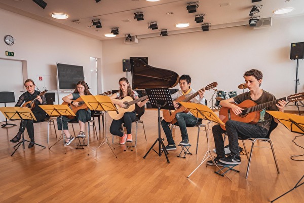 Junge Musizierende mit einer Gittarre.