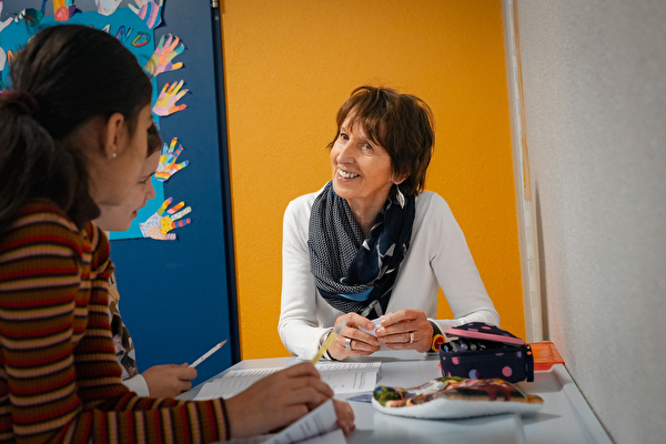 Eine Seniorin mit zwei Kindern am Pult.