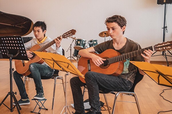 Zwei Jugendliche an der Gitarre.