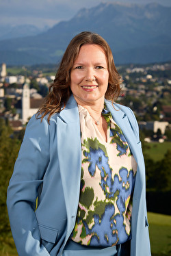 Frau, hellblauer Anzug, farbige Bluse, lächelnd