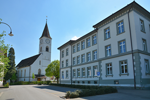 Ansicht Nord-West Primarschulhaus Dorf neben Ref. Kirche St. Jakob