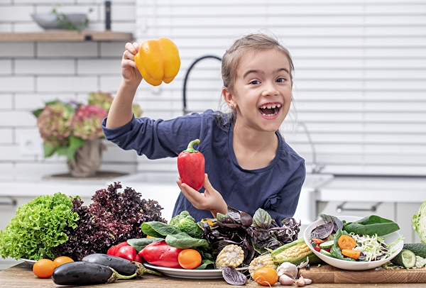 Bild eines Mädchens mit zahlreichen Gemüsesorten.