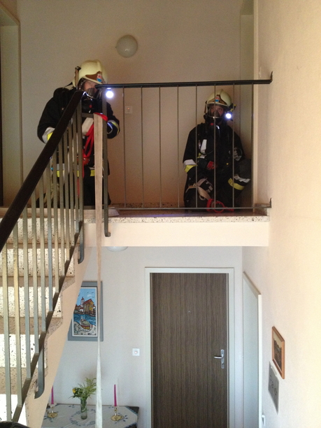 Atemschutztrupp bei der Bereitstellung der Wasserleitung vor dem öffnen einer Wohnungstür.