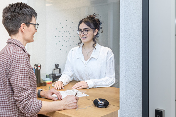 Lernende bedient am Schalter eine  Kundin