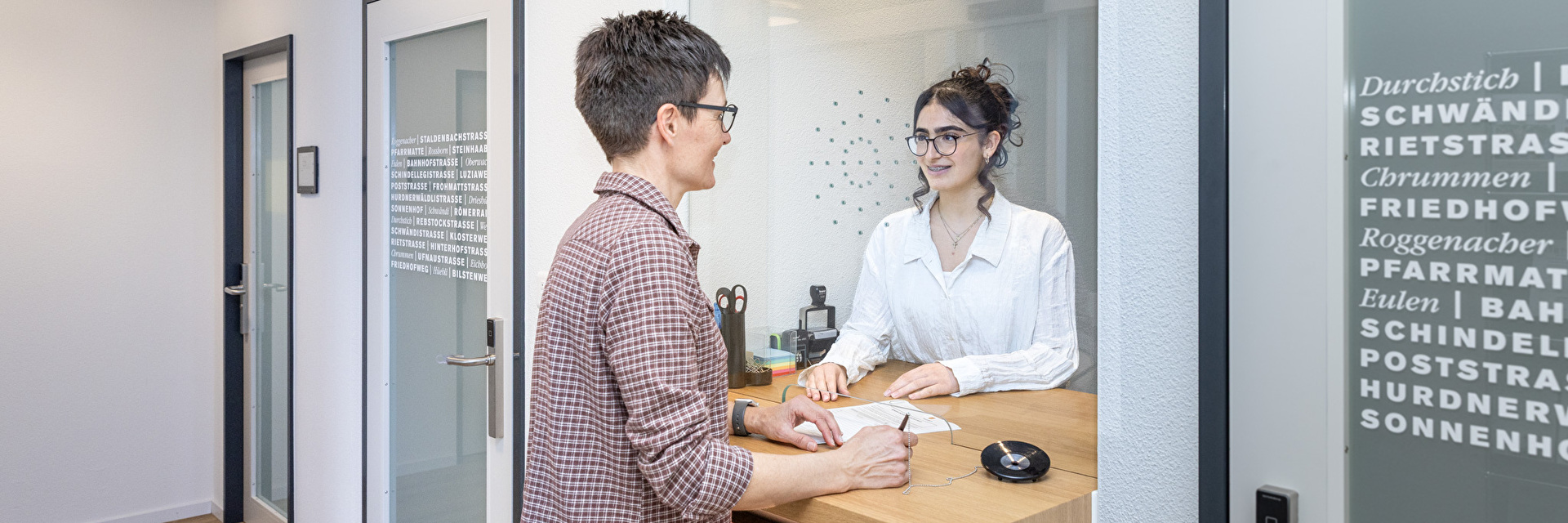Lernende bedient am Schalter eine  Kundin