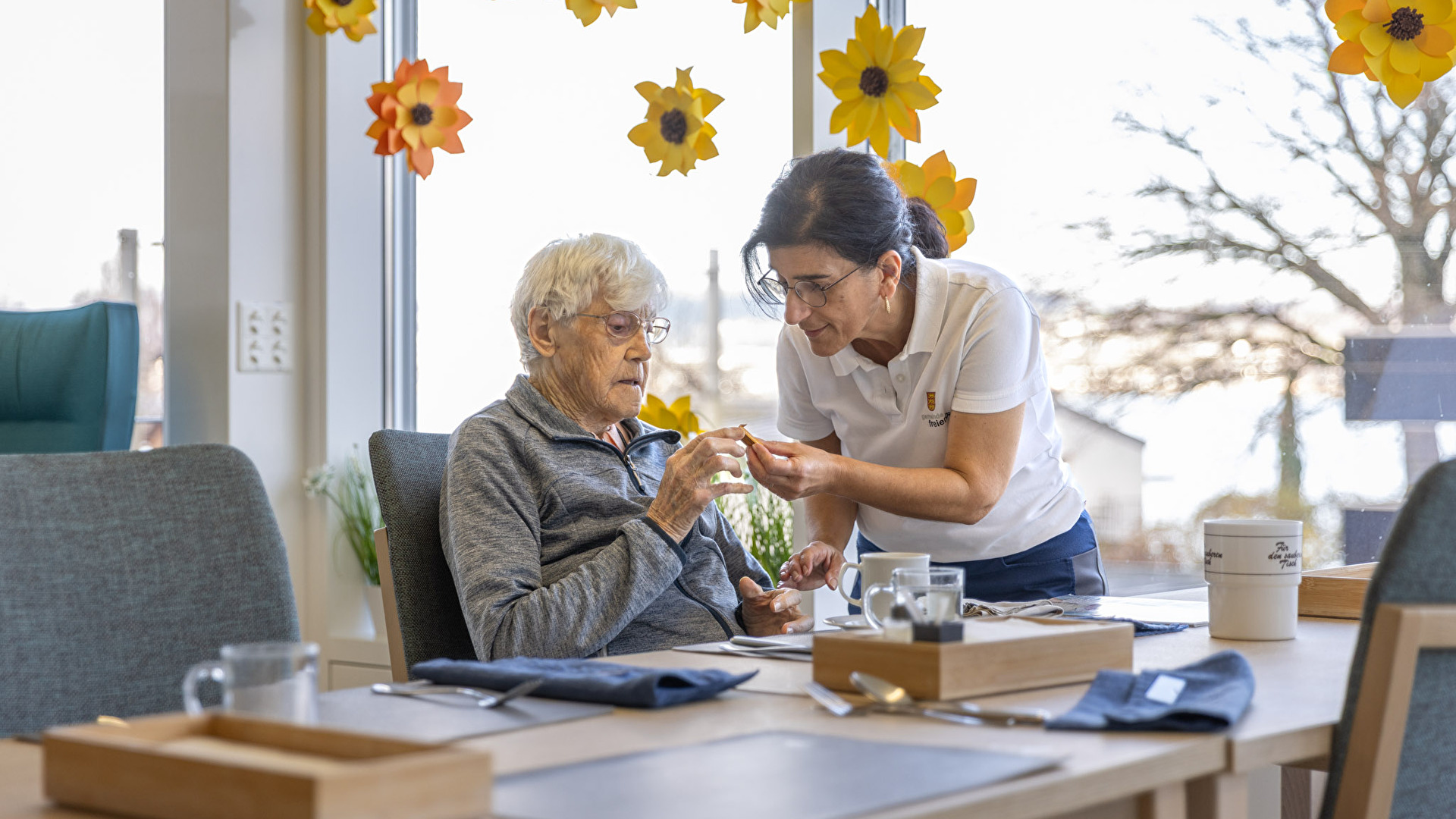 Frau hilft älterer Dame beim Essen