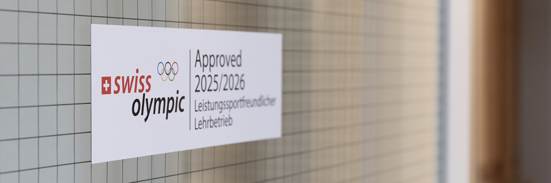 Swiss Olympic Label Leistungsfreundlicher Lehrbetrieb an einer Türe im Gang
