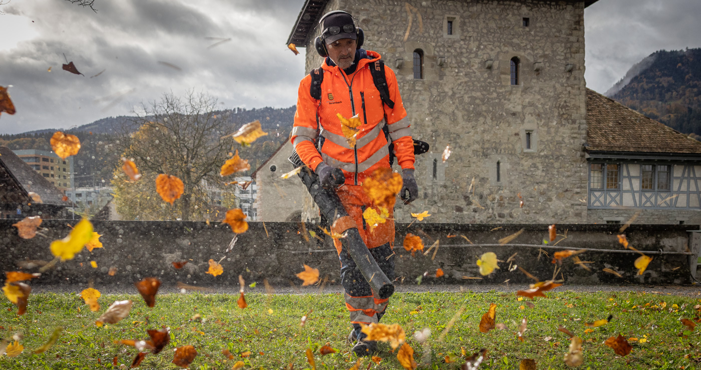 Werkhofmitarbeiter vor dem Gemeindehaus Schloss mit dem Laubbläser