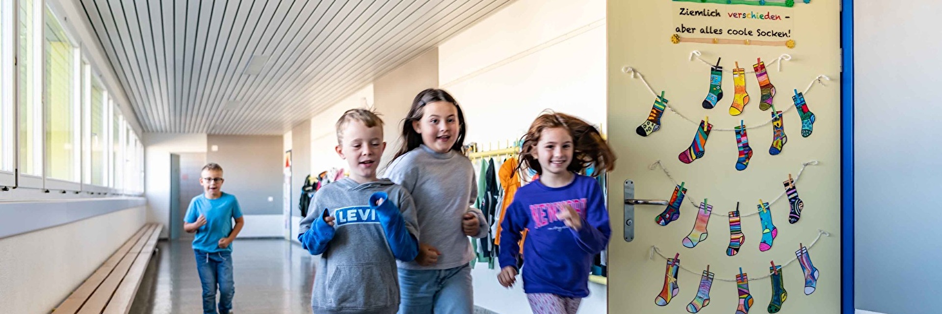 Kinder rennen durch den Gang im Schulhaus